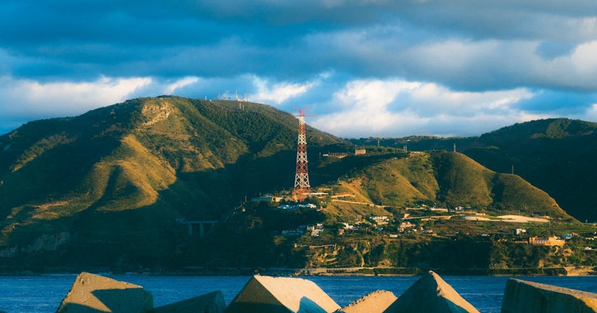 Majestic hills and ocean captured during sunset, featuring a prominent radio tower.