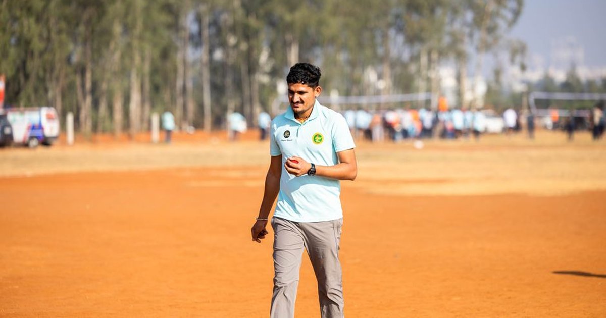 Young man in sportswear walking alone on an outdoor dirt field during daytime.