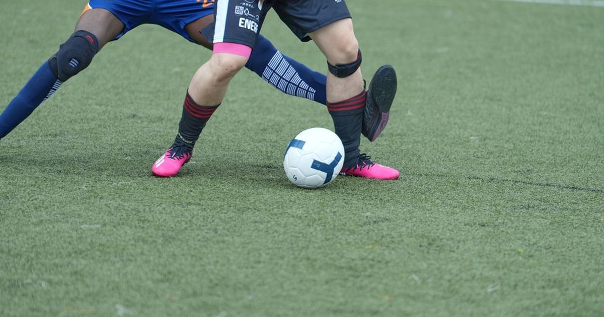 Two soccer players competing for the ball on a grassy field during a match.