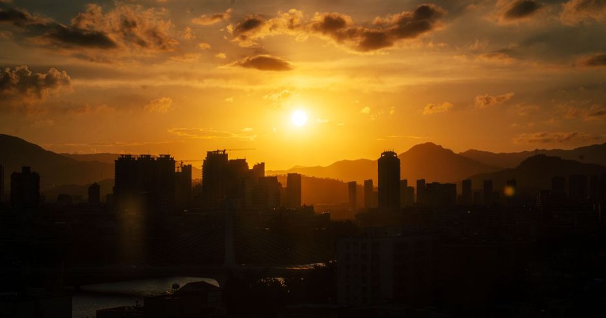 Stunning sunset over Xiamen city skyline with silhouetted skyscrapers and golden clouds.