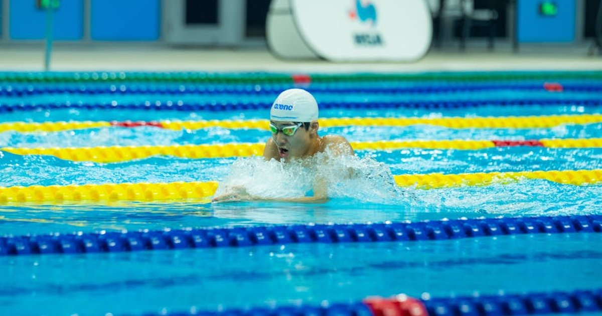 Swimmer racing in an indoor competition pool, captured mid-stroke, showcasing athletic ability.