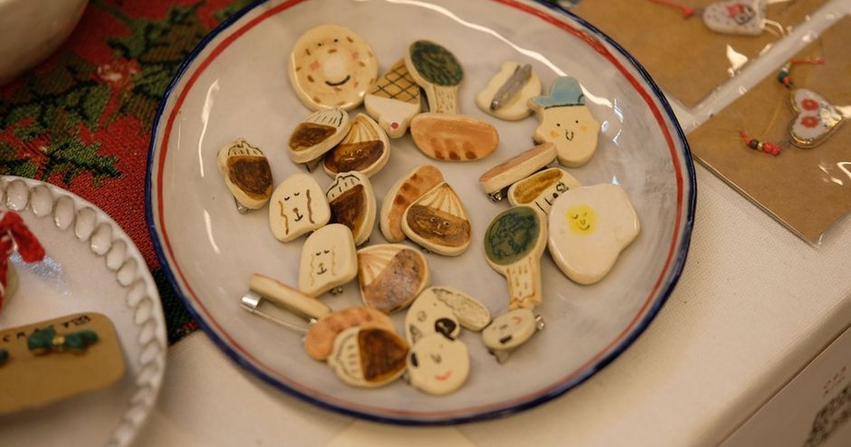 Cute baked clay jewelry shaped like breads and pastries on display plate.