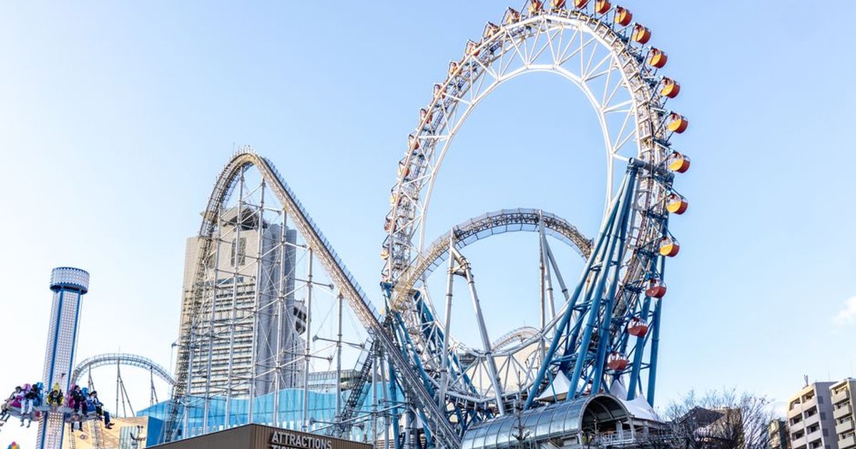 Vibrant Ferris wheel and roller coaster at Tokyo Dome City amusement park during daytime.
