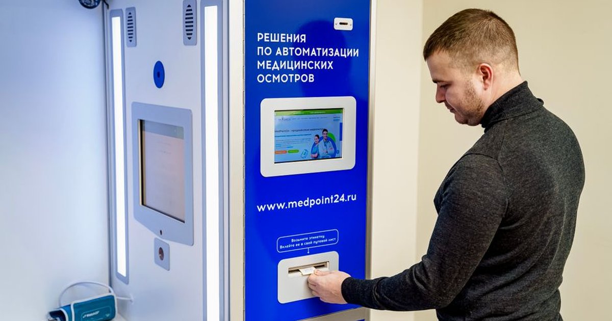 A person interacts with an automated medical kiosk featuring health technology solutions.