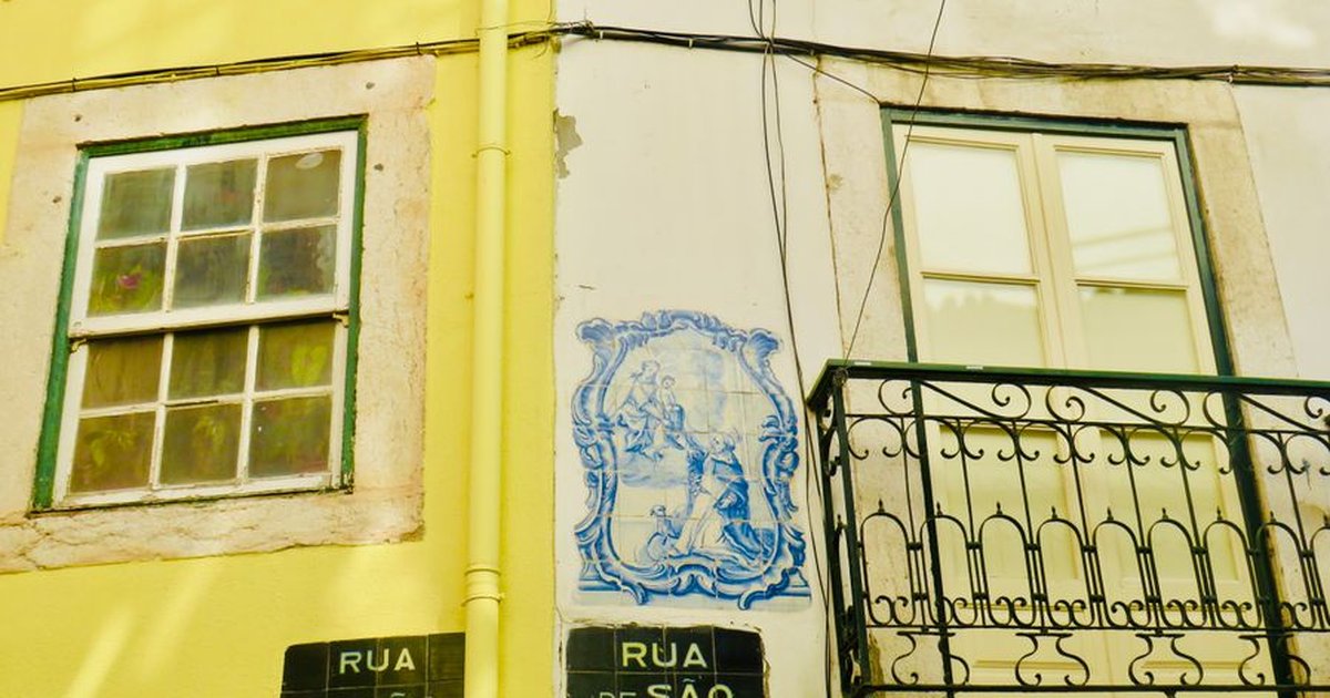 Charming Lisbon street featuring azulejos, balconies, and vibrant architecture.