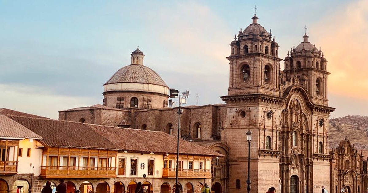 Scenic view of a historic church in Cusco, Peru with people walking at sunset.