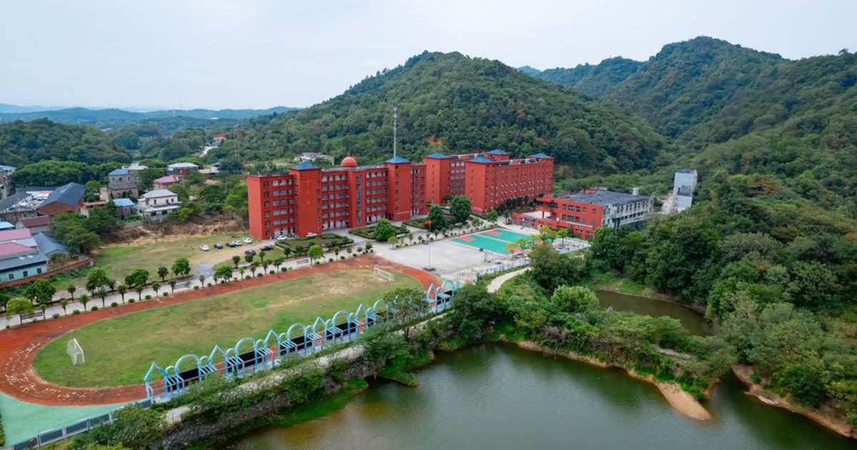 Scenic aerial view of a red brick campus nestled in a green valley with mountains.