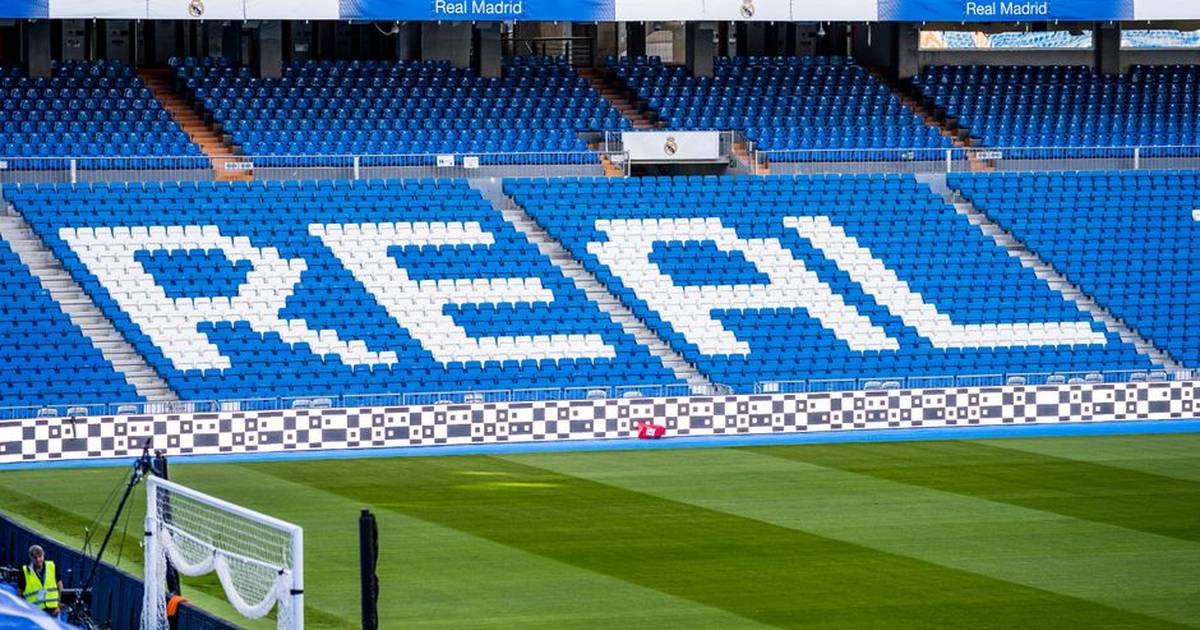 Empty seating area in Real Madrid's stadium with 'REAL' prominently displayed in white.