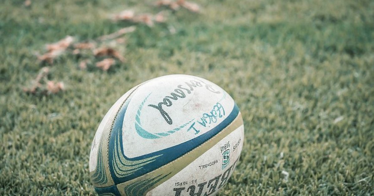 A close-up shot of a rugby ball resting on a grass field, ideal for sports theme.