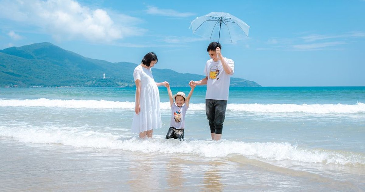 Happy family enjoying a sunny day at Da Nang Beach, Vietnam, playing in the waves.