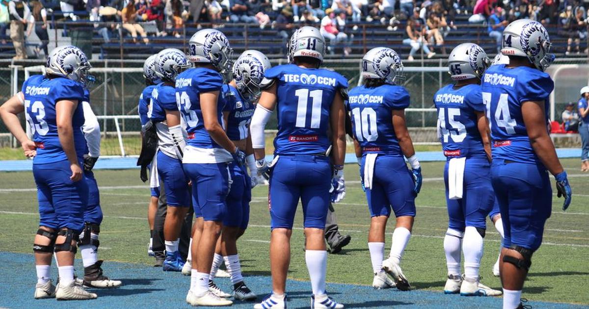 Team in blue uniforms huddled on a sunny day during an American football game