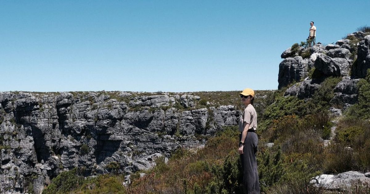 Two adults exploring rugged terrain on Table Mountain in Cape Town, surrounded by stunning natural landscapes.