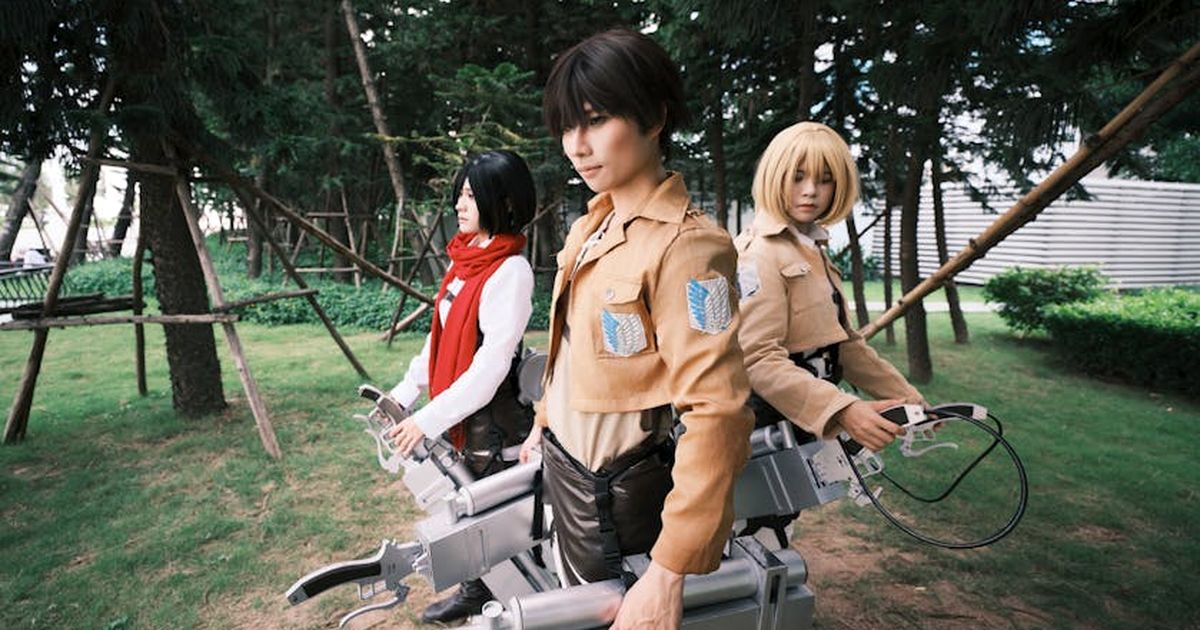 Diverse group of cosplayers posing in character outfits in an outdoor forest area.