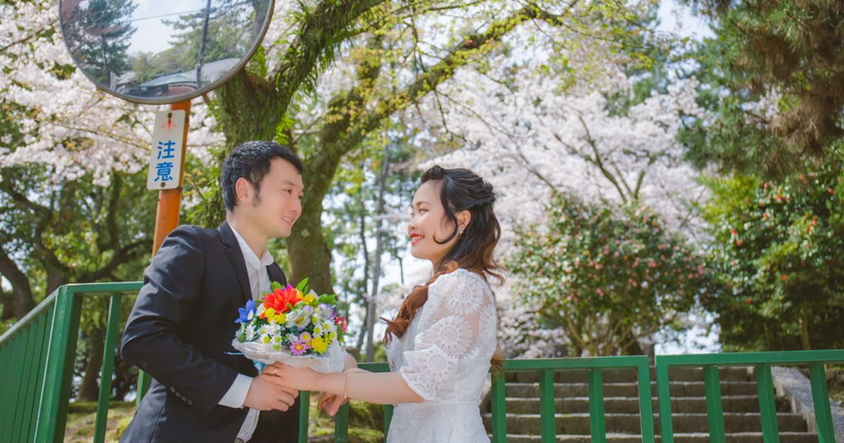 A happy couple sharing a moment under blooming cherry blossoms on a sunny spring day.