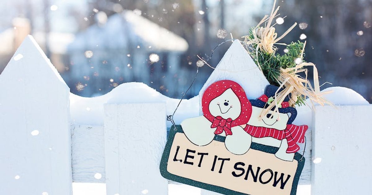 Festive winter scene with a whimsical 'Let It Snow' sign on a snowy fence.