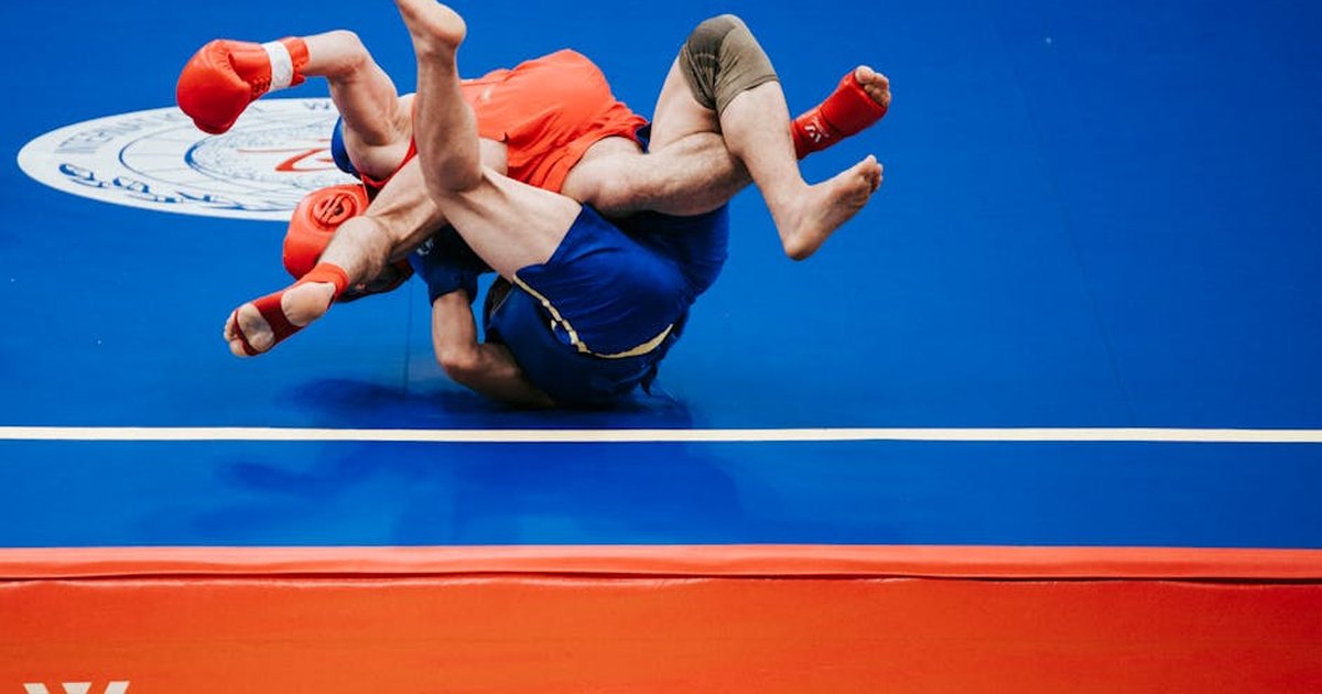 Two athletes engaged in an intense wrestling match on a blue mat.