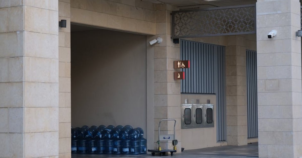 Entrance with stacked water coolers, modern architecture, and restroom signage.