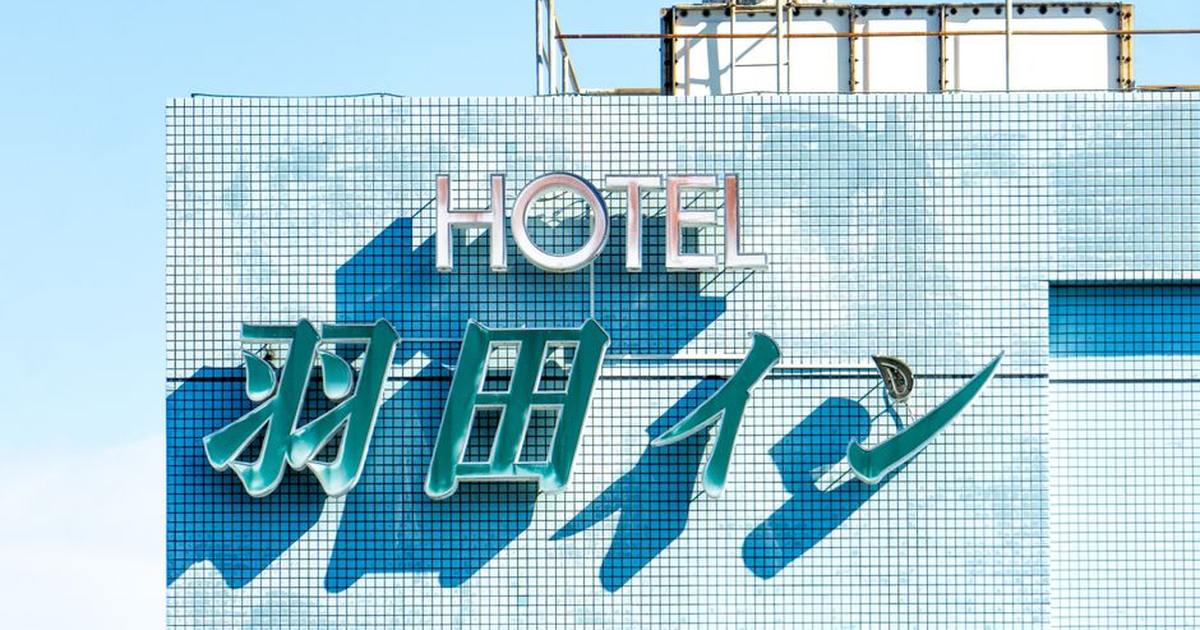 Brightly lit hotel sign with blue tiles under a clear sky, showcasing modern architecture.