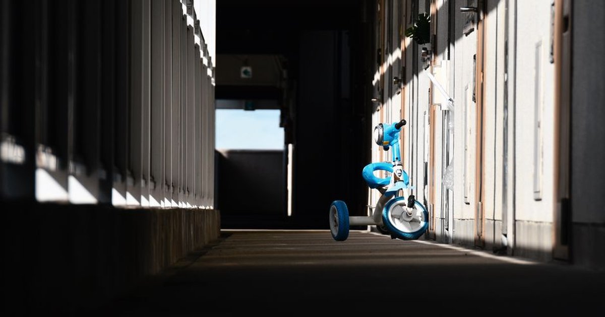 Minimalist image of a blue tricycle on a sunlit urban pavement.