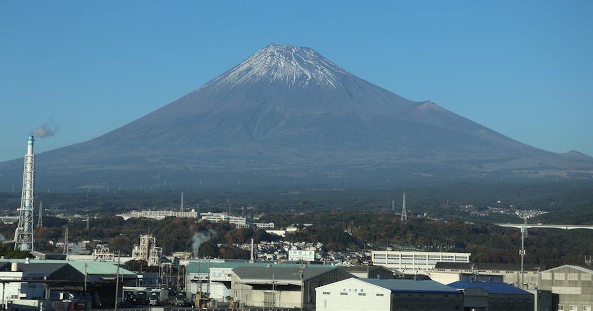 Mount Fuji towers over the industrial backdrop in Oyama, Shizuoka, Japan. Clear skies highlight this iconic peak.