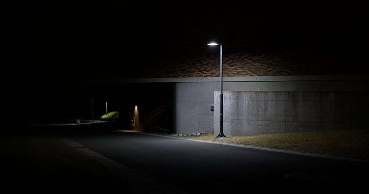 A dramatic night street scene featuring a lone streetlight illuminating a path in Kyoto, Japan.