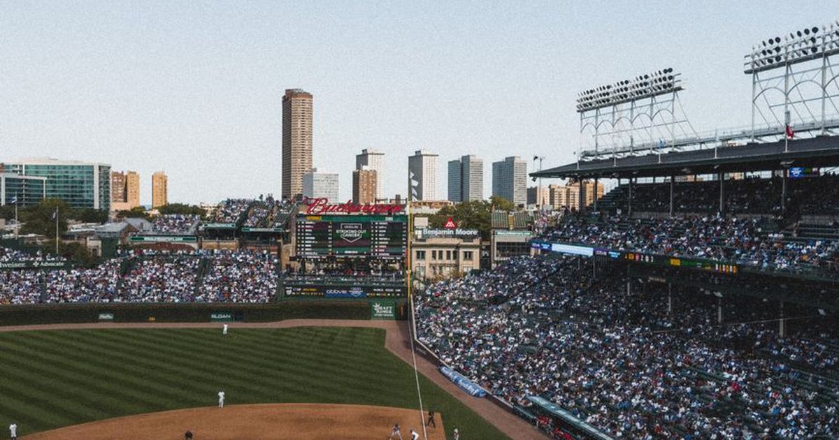 Crowded baseball stadium under a clear sky with cityscape background. Energetic game day atmosphere.