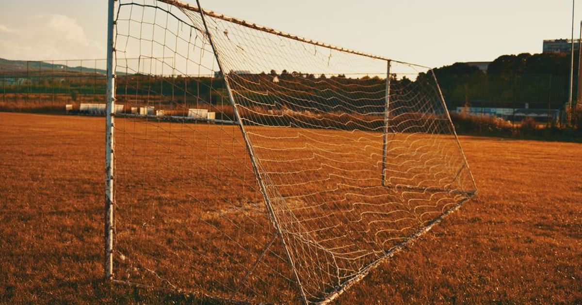 A quiet soccer field with a goalpost at sunset, reflecting a peaceful atmosphere.