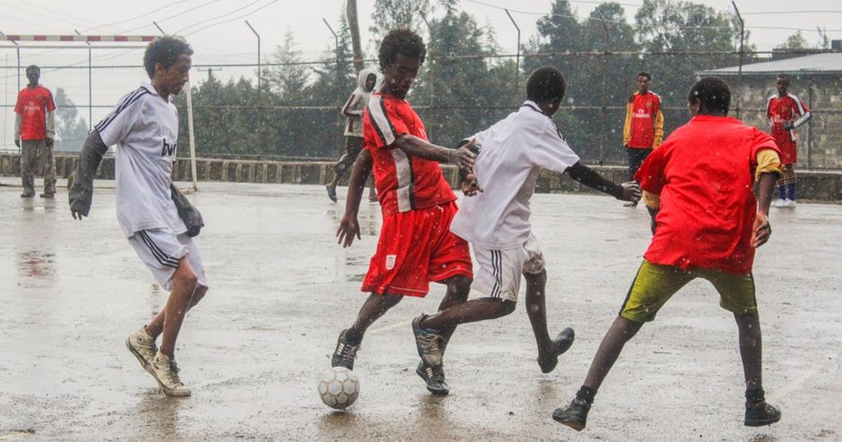 Youth playing a competitive soccer game in the rain, showcasing teamwork and energy.