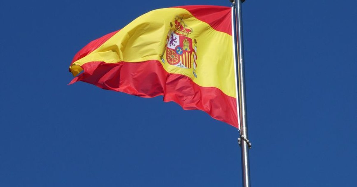 A vibrant Spanish flag prominently waving against a clear blue sky, symbolizing national pride.
