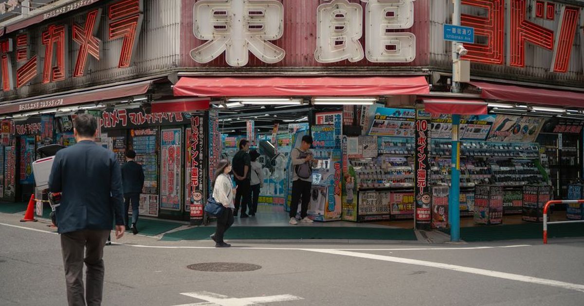 Daytime view of a busy electronics store in Tokyo with people shopping outside.