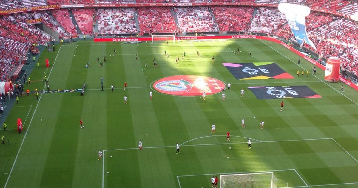 Aerial view of a soccer field during a match in a packed stadium with players and fans.