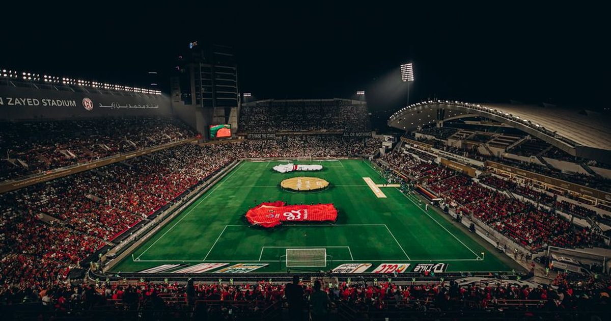 Aerial view of a lively football match at Zayed Stadium, showcasing fans and vibrant atmosphere.
