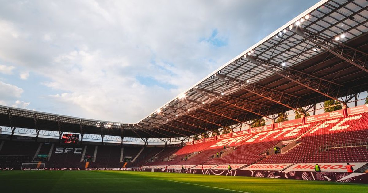 Wide-angle shot of Geneva's SFC stadium with empty seats and sky highlights.