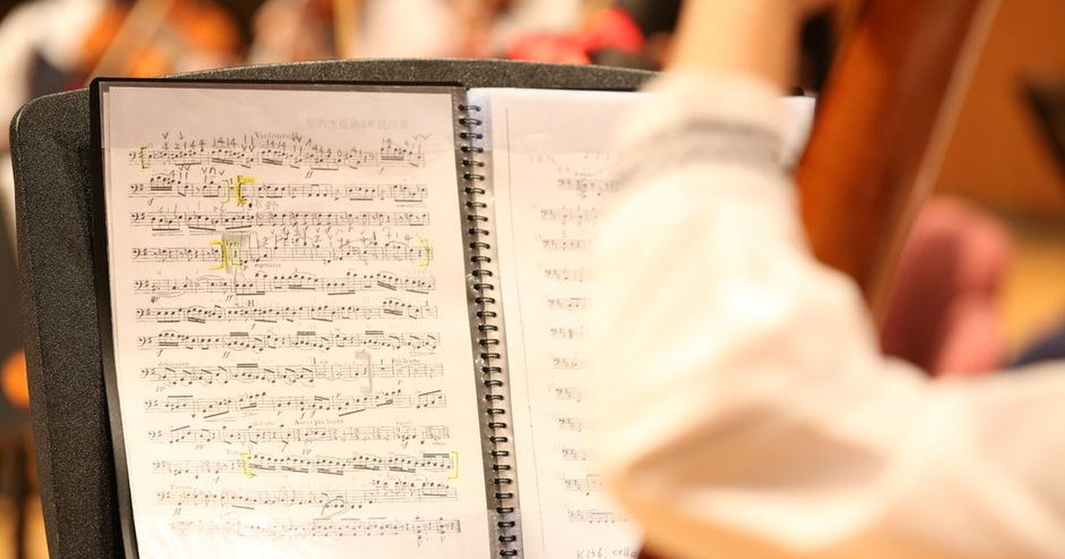 Detailed view of musical notes on sheet music during an orchestra rehearsal.