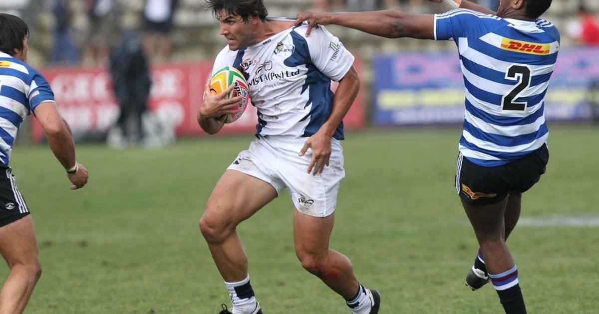 Rugby players in motion during a competitive game on a grassy field.