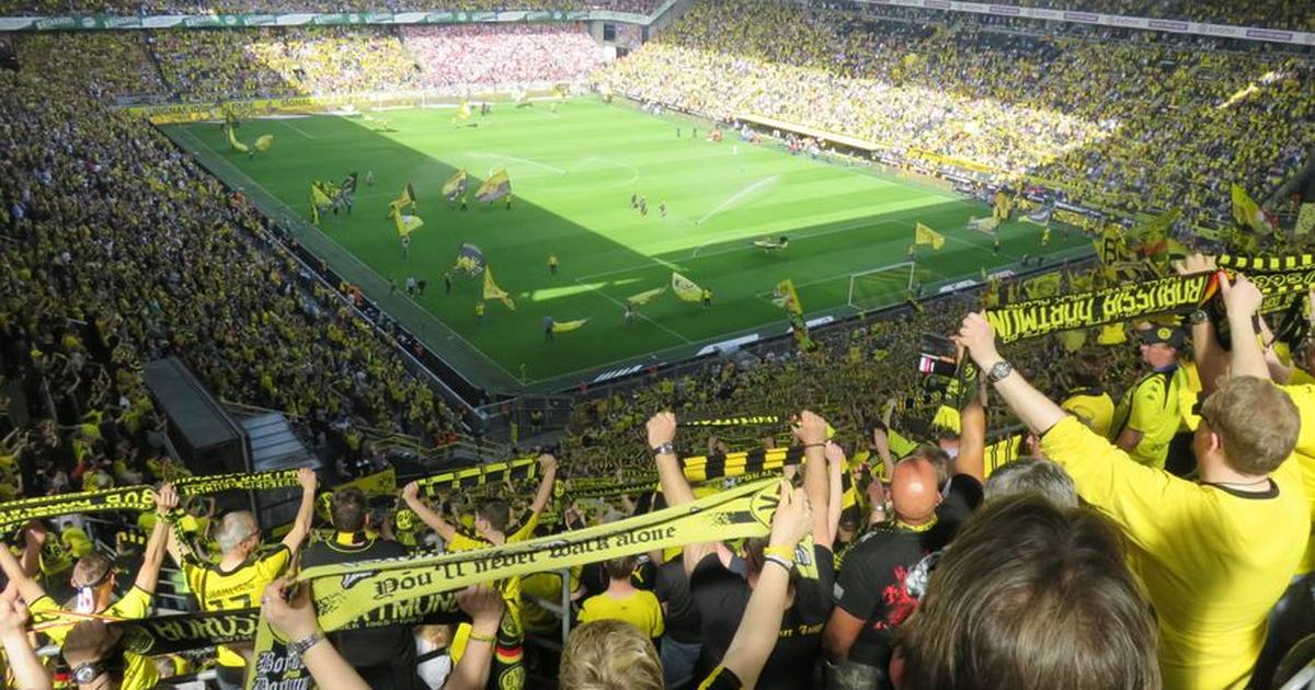 Excited Borussia Dortmund fans cheering during an intense soccer match at the stadium.