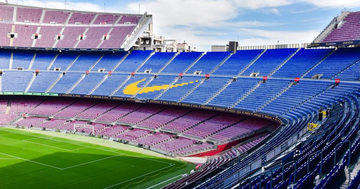 A wide-angle view of the iconic empty stands at Camp Nou, Barcelona's renowned football stadium under a clear sky.