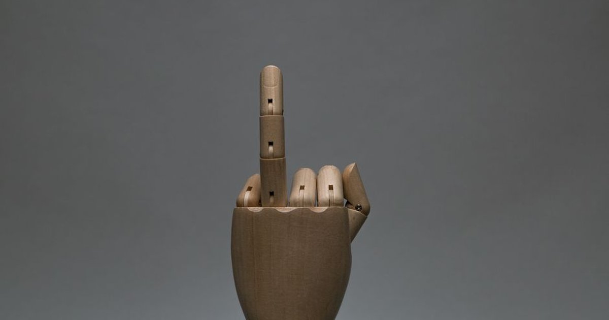 A wooden mannequin hand displaying a gesture against a gray background.
