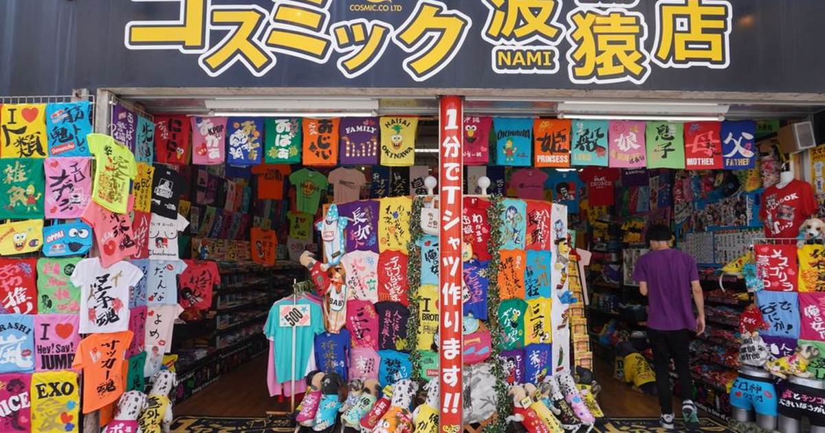 Colorful T-shirt display in a vibrant urban Japanese clothing store entrance.