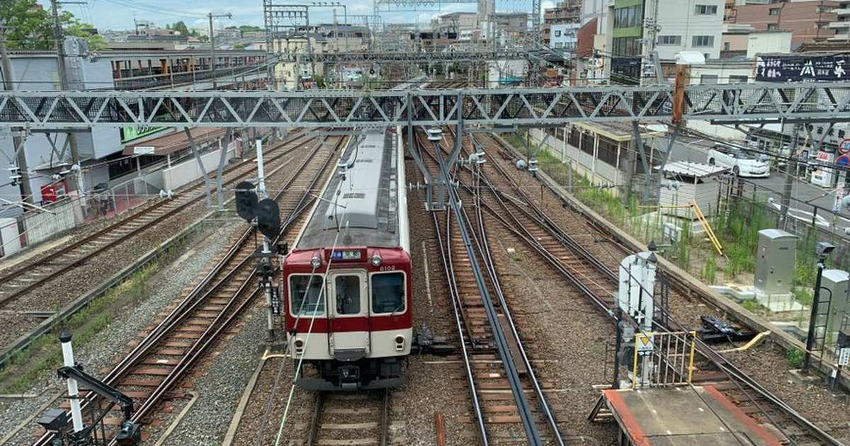 A train navigating through complex railway tracks in Nishinomiya, Japan, under an overcast sky.