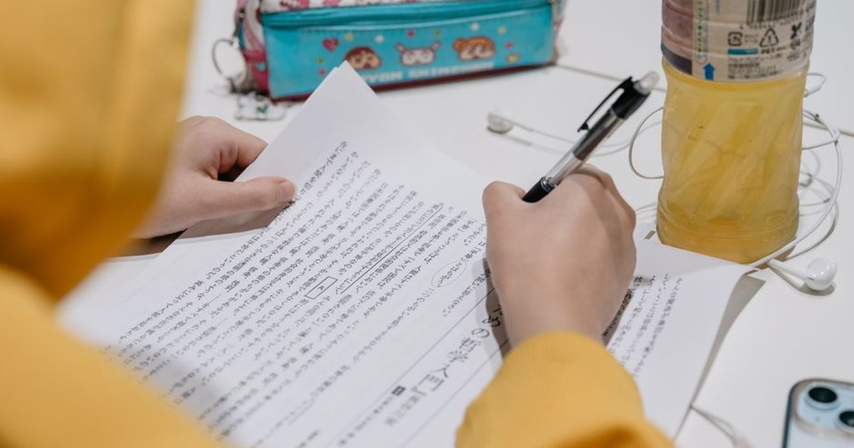 Close-up of individual studying Japanese text with colorful stationery on desk.