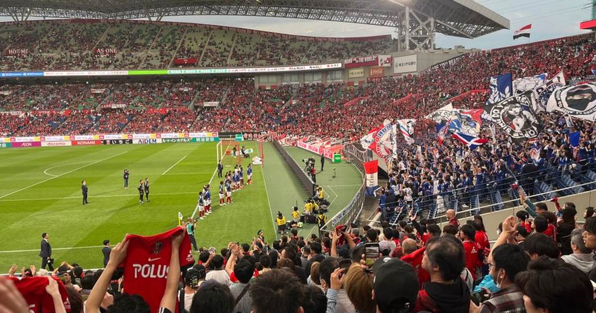 Energetic crowd cheering at a soccer match in Saitama Stadium, Japan.