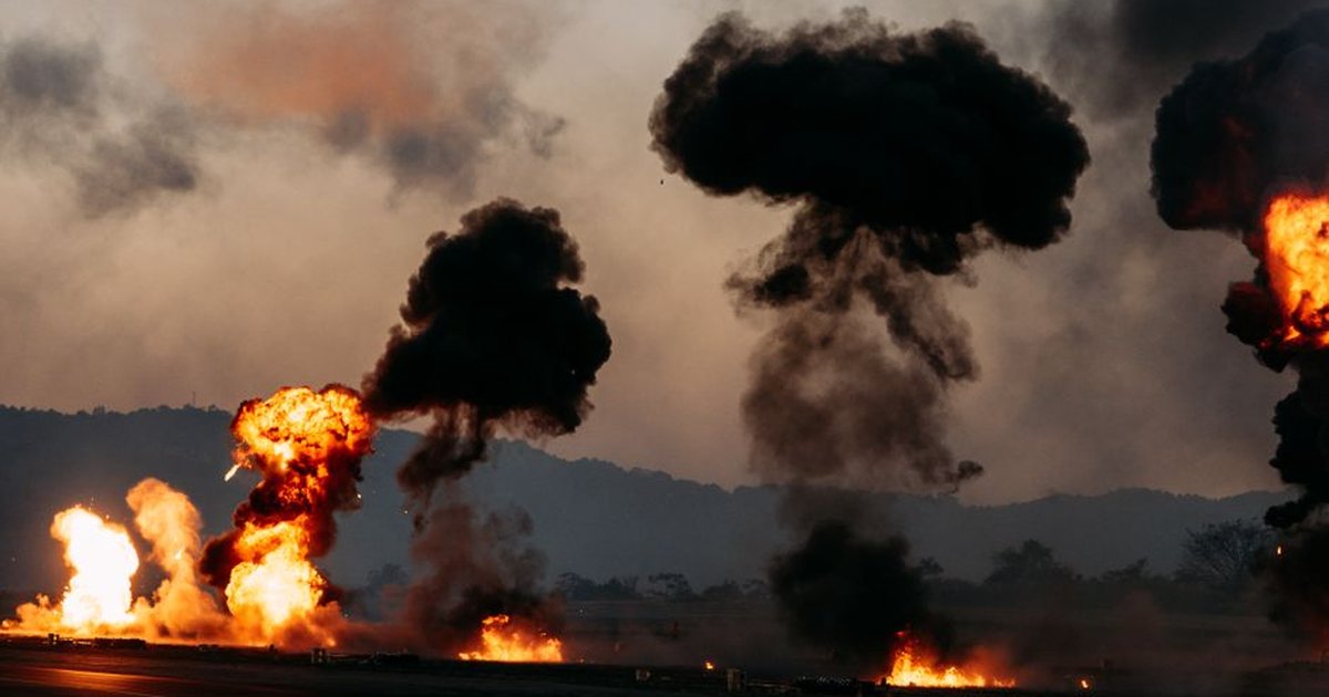 Dramatic scene with explosions and thick black smoke rising in an outdoor setting.