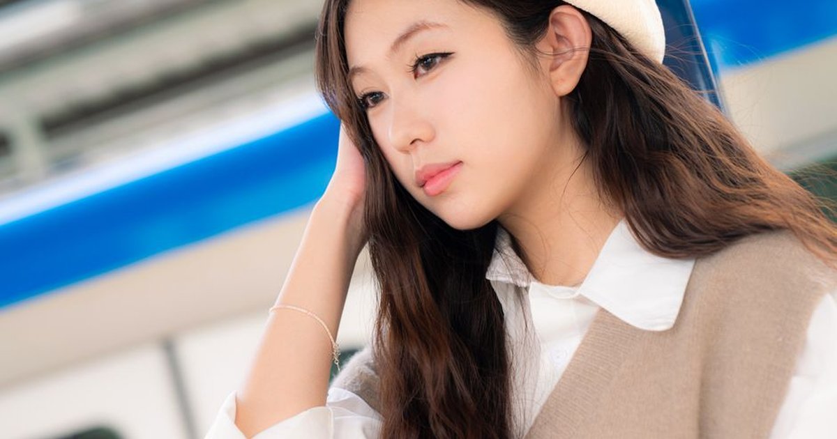 Stylish young woman with beret waiting at a train station, outdoors.