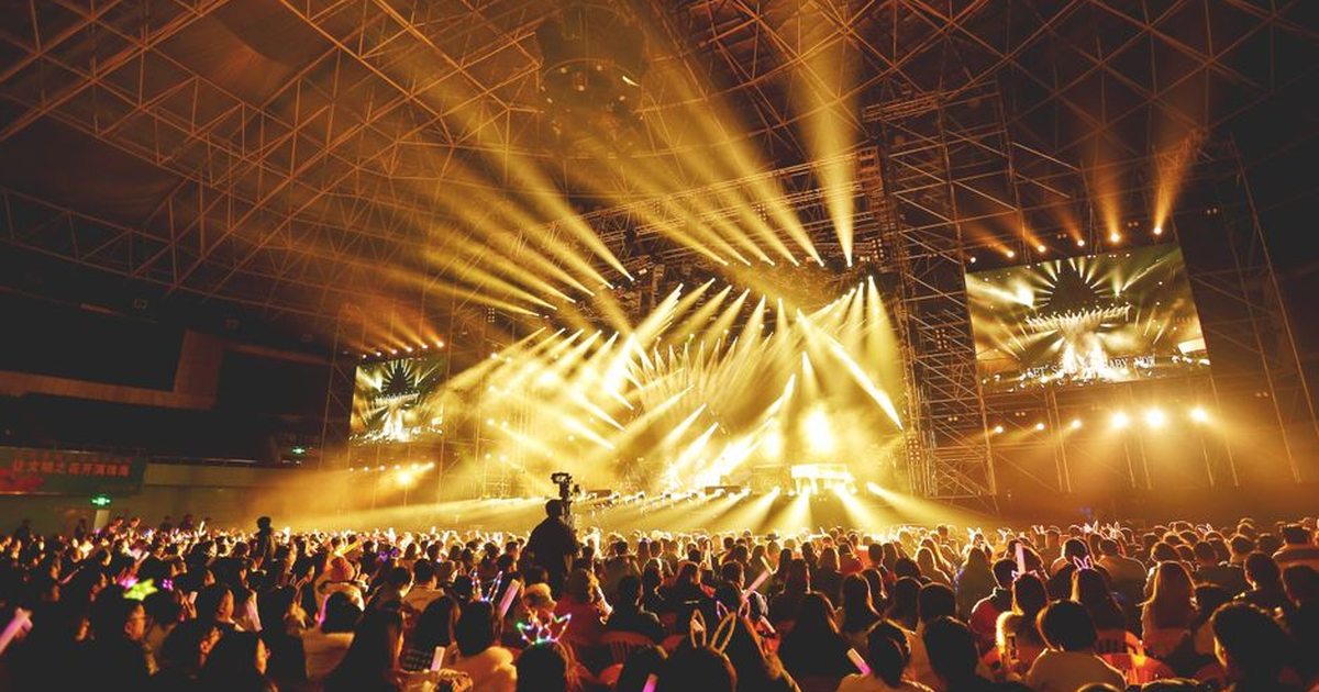 Dynamic concert scene with vibrant crowd and dazzling stage lights indoors.