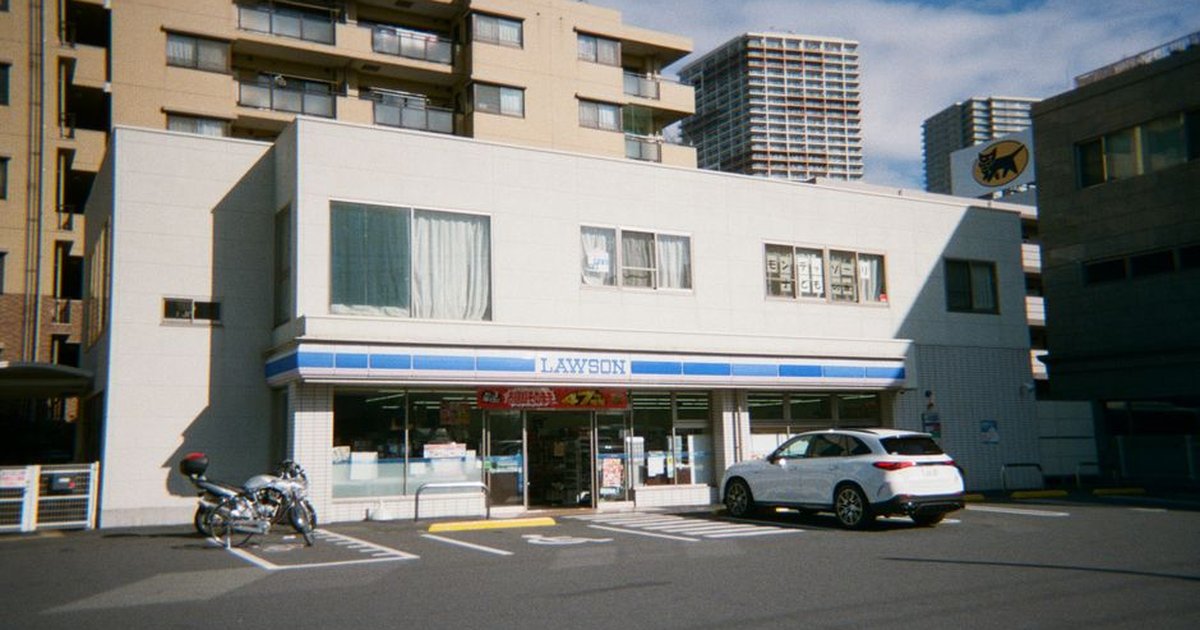 A Lawson convenience store in a city with high-rise buildings around, showcasing urban life.