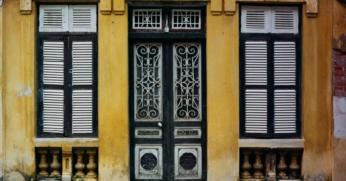 A classic vintage facade featuring wooden doors and shuttered windows with intricate designs.