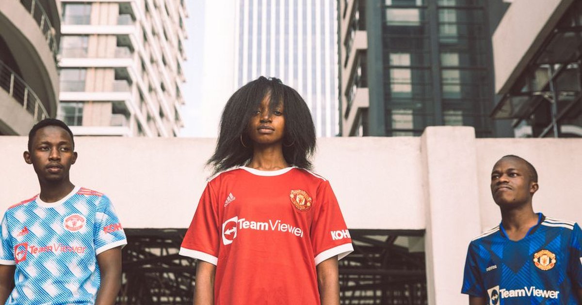 Three young adults in sports jerseys pose confidently in an urban Kenyan setting.