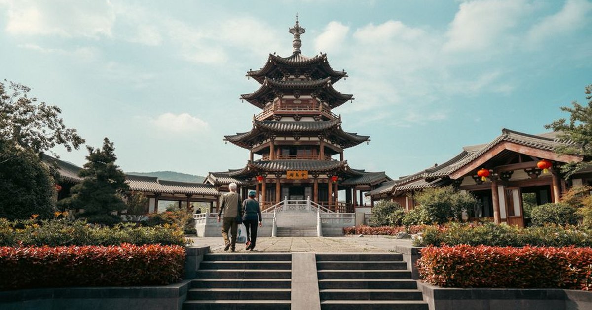 Photograph of the Jin Wu Pavilion in Nanjing, showcasing traditional Chinese architecture with two people walking towards it.
