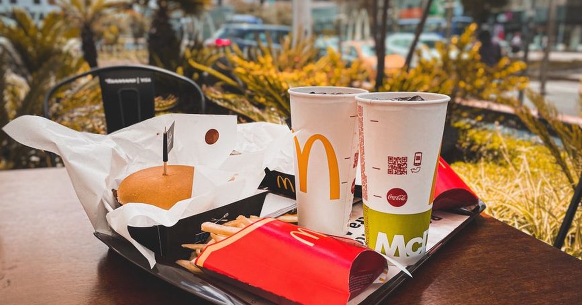 An appetizing fast food meal with burger, french fries, and drinks on an outdoor table in urban setting.